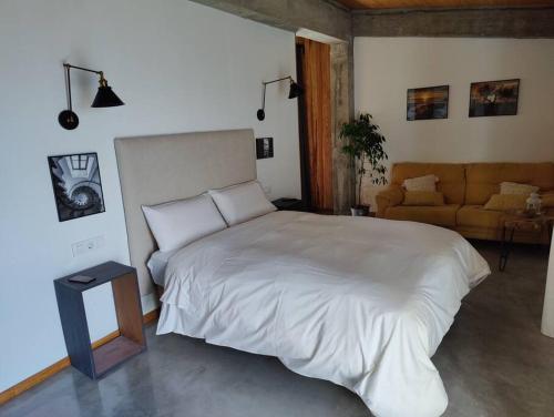 a bedroom with a large white bed and a couch at Apartamento nuevo con vistas a las Islas Cíes in Cangas de Morrazo