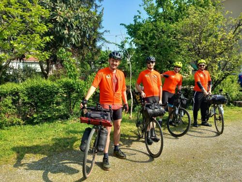 un grupo de hombres con camisas naranjas parados con sus bicicletas en B&B delle Arti en Crema