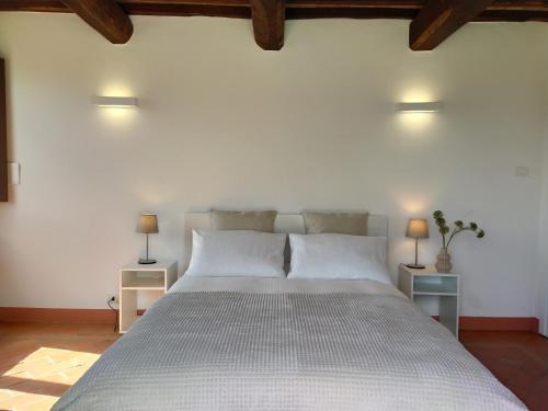 a bedroom with a large white bed with two lamps at Poggio ai Gelsi in Pienza