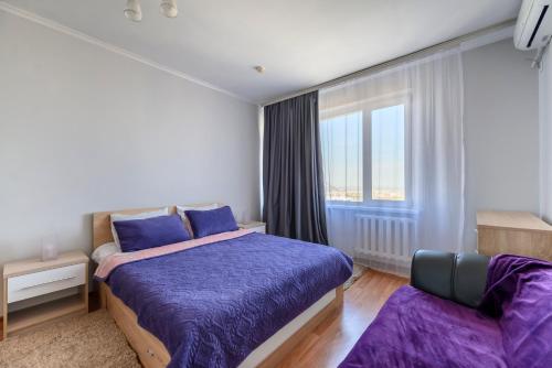 een slaapkamer met een paars bed en een raam bij ЖК Айгерим in Alma-Ata