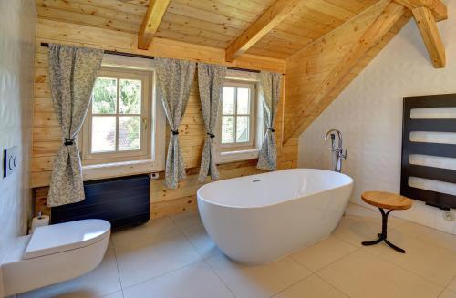 a bathroom with a large tub and a wooden ceiling at Roubenka pod Troskami in Ktová