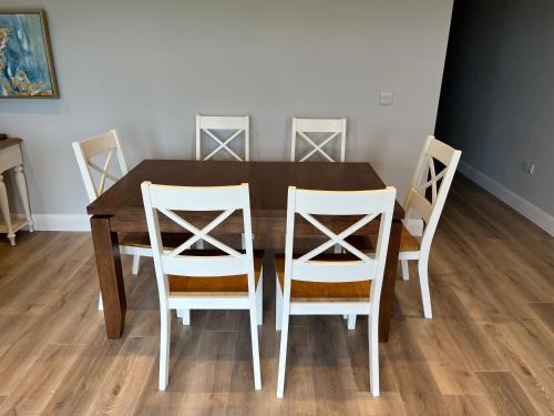 a dining room table with four white chairs around it at Knockreagh Farm Cottages Mountain or Cedar views in Kilkenny