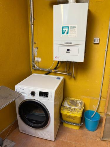 a washer and dryer in a room with a yellow wall at Apartment Golden Dreams in Reggio Calabria