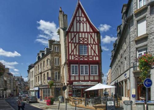 ein hohes rotweißes Gebäude in einer Stadtstraße in der Unterkunft Cosy house in Guingamp ! in Guingamp