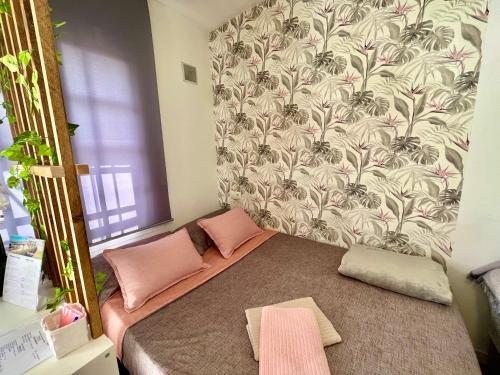 1 dormitorio con cama con almohadas rosas y papel pintado en Acogedor loft en recinto privado - Terapia Salada, en Estepona