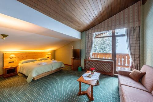 a hotel room with a bed and a couch at Hotel Sochers Club in Selva di Val Gardena