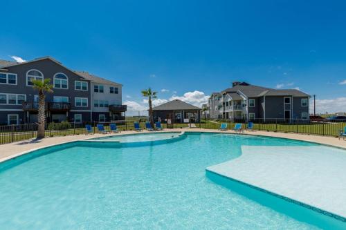una gran piscina con sillas azules y apartamentos en condominio en Peaceful Seaside Condo-Walking Path to the Beach en Corpus Christi
