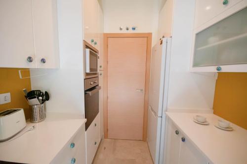 uma pequena cozinha com armários brancos e uma porta em For Your Rentals Bonito Apartamento cerca Bernabeu MJU14B em Madri