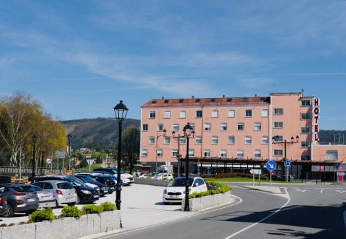 a parking lot with cars parked in front of a building at Hotel Eumesa in Puentedeume