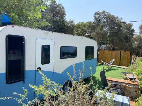 a blue and white trailer parked in a yard at Countryside, beach view glamping caravan in HaBonim