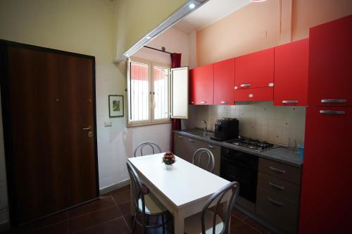 une cuisine avec des placards rouges et une petite table. dans l'établissement Luxury Apartment Golden Dreams, à Reggio de Calabre