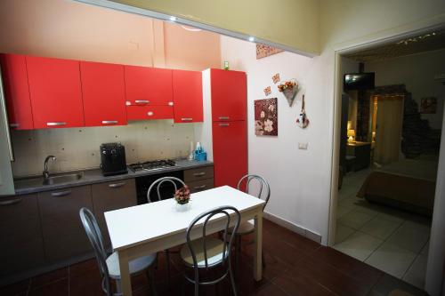 a kitchen with red cabinets and a white table and chairs at Apartment Golden Dreams in Reggio Calabria