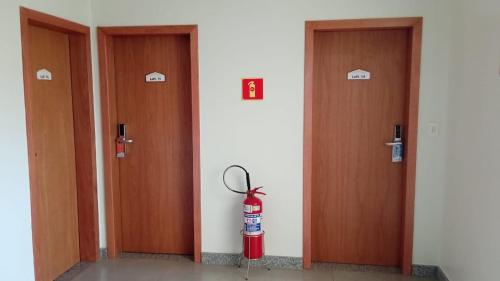 a room with three doors with a fire extinguisher in the middle at Edifício Master in Cascavel