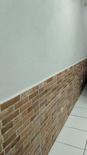 a brick wall next to a white tile floor at Edifício Master in Cascavel