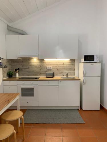 a kitchen with white cabinets and a white refrigerator at Monte do Pereiro in Santiago do Cacém