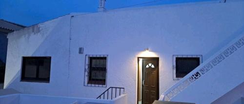 a white building with a black door and stairs at Guest House Casa Ramos on the Strip in Albufeira