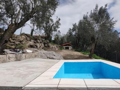 a blue swimming pool with a house in the background at Cantinho da Pereira in Lugar
