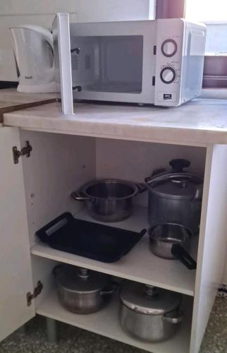 a kitchen shelf with a microwave and some pots and pans at Guest House Casa Ramos on the Strip in Albufeira