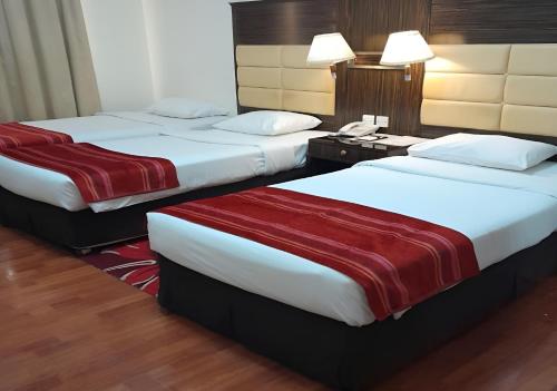 a hotel room with two beds with red and white sheets at Fortune Deira Hotel in Dubai