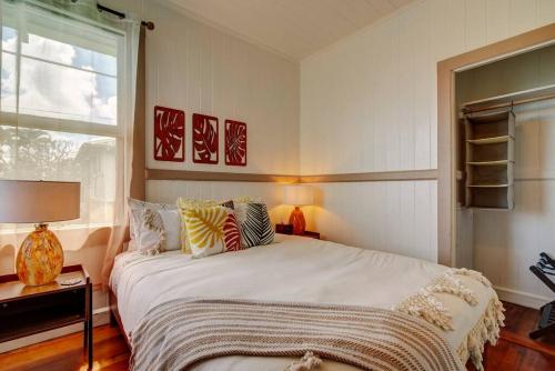 Un dormitorio con una gran cama blanca y una ventana en NEW Paddler's Inn- 3BR Hilo Downtown, en Hilo