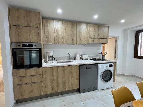 Una cocina con muebles de madera y lavadora. en A COLETTA, en Piana