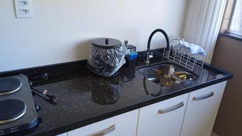 a kitchen counter with a sink and a stove at Edifício Master in Cascavel