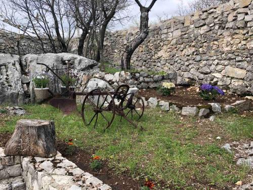 a garden with a stone wall and a stone cart at Vila Agroturizam Kućica Mostar-Welcome bikers in Mostar
