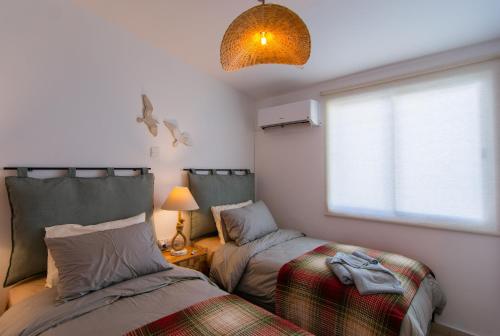 a bedroom with two beds and a window and a lamp at Akamas Sunset Boho Chic Maisonette by ONE VILLAS in Polis Chrysochous