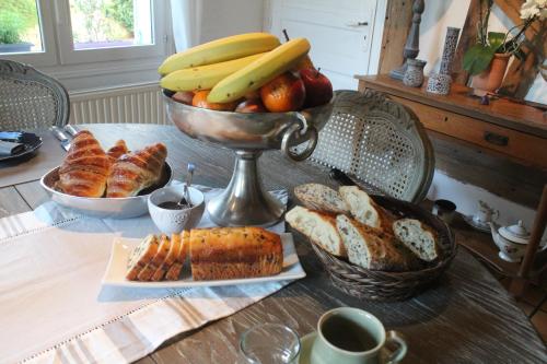 a table with a bowl of bananas and bread and fruit at B&B les Agapanthes in Gasny