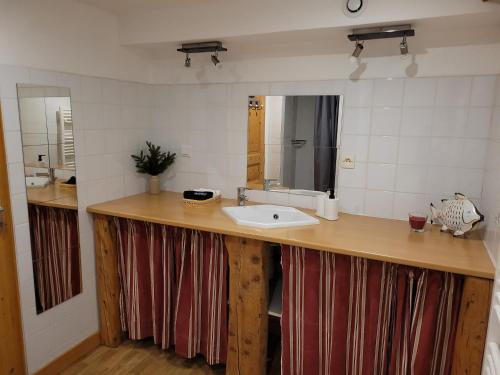uma casa de banho com um lavatório e um espelho em 7 p - Au cœur du massif jurassien em Les Rousses