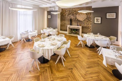a dining room with white tables and chairs and a fireplace at Hotel Château de la Barbinière in Saint-Laurent-sur-Sèvre