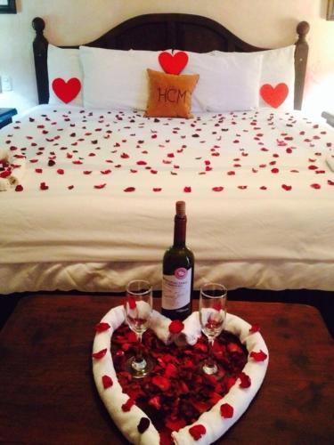 a bed with a bottle of wine and two glasses at Hotel Ciudad Blanca in Copan Ruinas