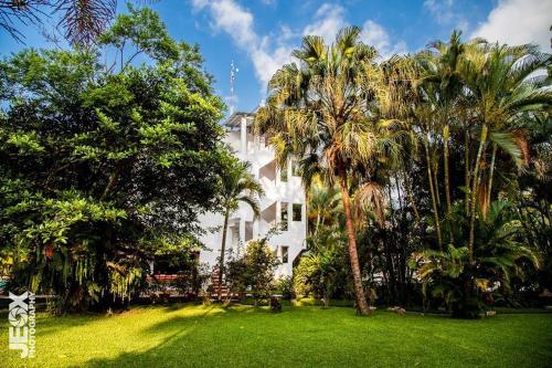 a white house with palm trees in front of it at Hotel Ciudad Blanca in Copan Ruinas