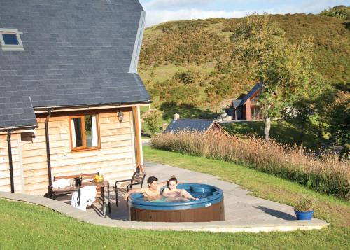 Slate House Lodges في Llandinam: شخصان في حوض استحمام ساخن في الفناء الخلفي