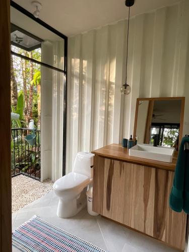 a bathroom with a toilet and a sink and a mirror at Casa Alba - Portasol Vacation in Savegre
