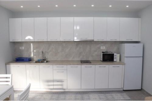 a kitchen with white cabinets and a white refrigerator at FAMILY-FRIENDLY APARTMENTS in Donji Štoj