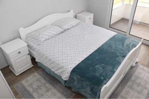 Schlafzimmer mit einem weißen Bett und einem Spiegel in der Unterkunft FAMILY-FRIENDLY APARTMENTS in Donji Štoj
