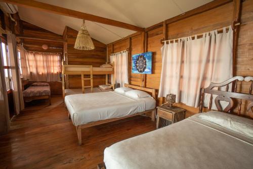 a bedroom with two beds and wooden walls at The Sea Garden House in Olón