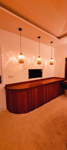 a bar in a room with three lights on the wall at Vaagali Inn in Keyodhoo