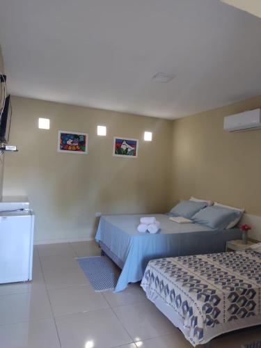 a bedroom with two beds and two pictures on the wall at Pousada Villa Manduca in Amontada