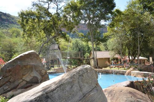 a swimming pool with a waterfall in a park at Rocky Drift Private Nature Reserve in Waterval Boven