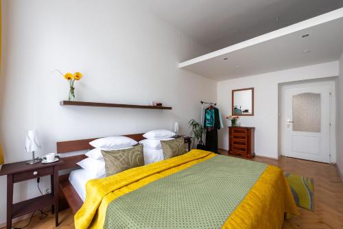 a bedroom with a large bed with a yellow blanket at Prague - Karlin Apartments in Prague
