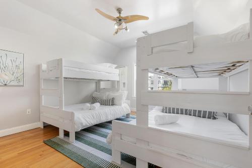 two white bunk beds in a room with a ceiling fan at Amazing family-friendly and group-friendly accommodation #TheBackDorch in Boston
