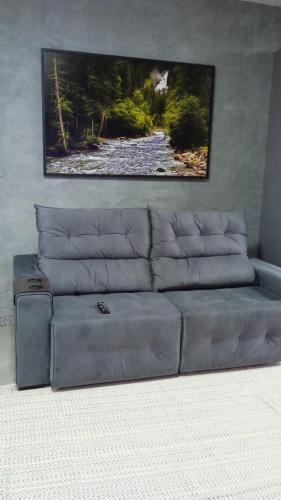 a gray couch in a living room with a picture on the wall at Edifício Master in Cascavel
