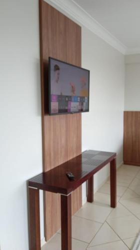 a table with a television on a wall with a tv on it at Edifício Master in Cascavel
