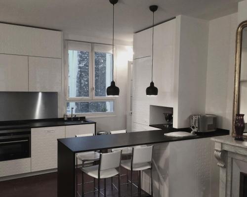 kuchnia z białymi szafkami i czarnym blatem w obiekcie Air conditioning Paris central stylish apartment w Paryżu
