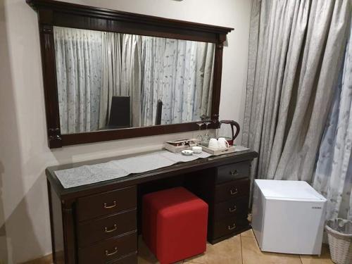 baño con tocador con espejo y taburete rojo en Roosthaven Guesthouse, en Centurion