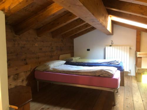 Baita Poira في Mello: سريرين في غرفة بجدران خشبية