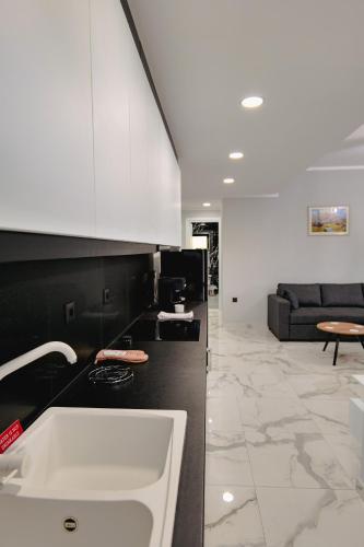 a kitchen with a sink and a living room at Iphigenia Luxury Flat in Sarandë