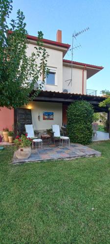 a house with a patio with white chairs in the yard at Kalendes in Kalandra